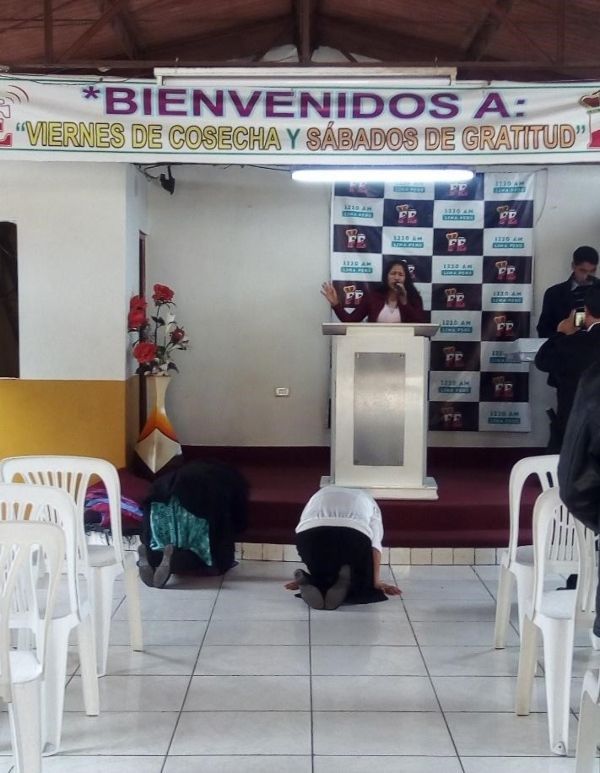 Fieles del aposento se arrodillan frente al estrado durante los cánticos